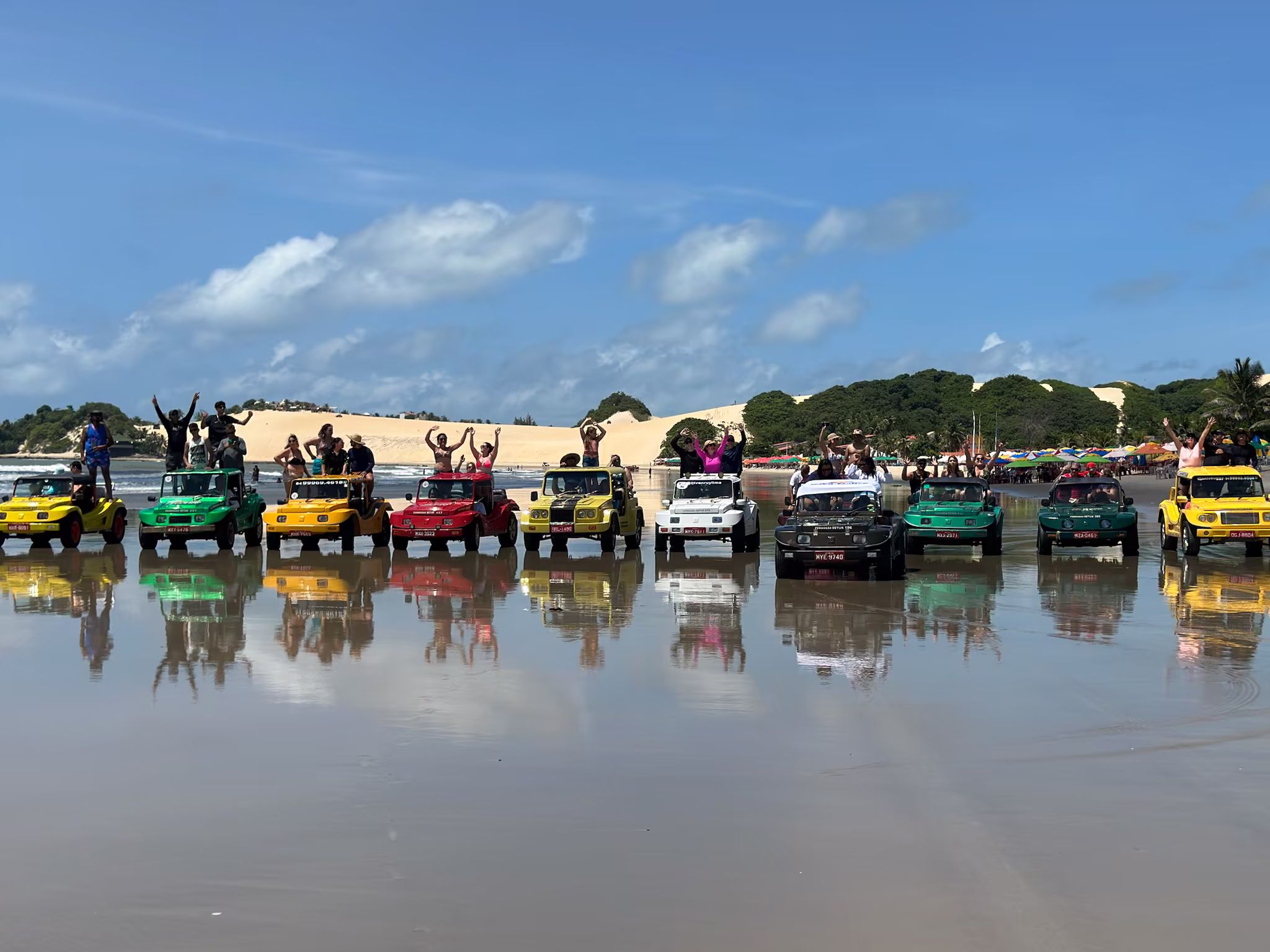 Frota de buggies coloridos refletidos na praia molhada